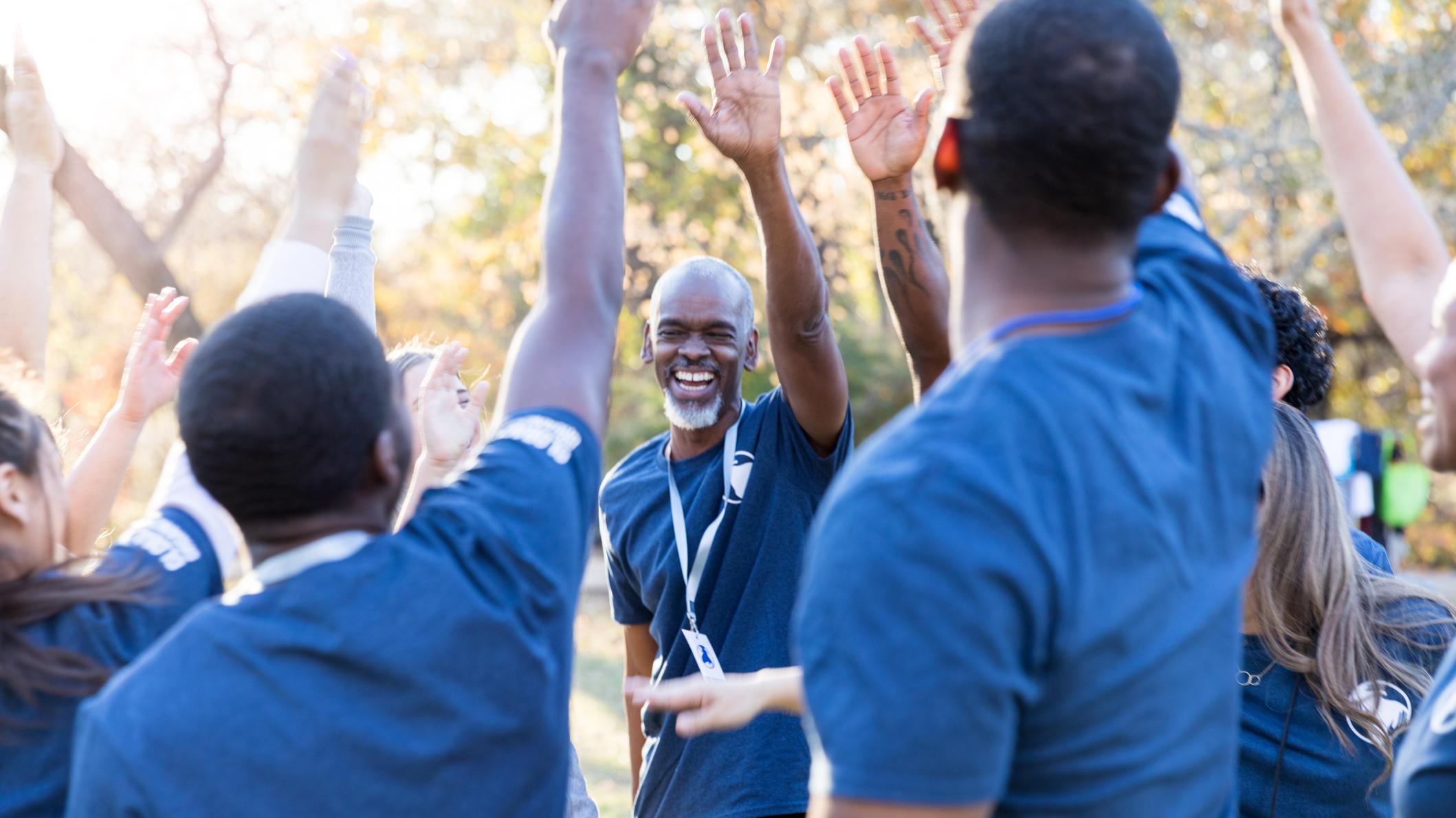 Circle of volunteers with hands up in the air